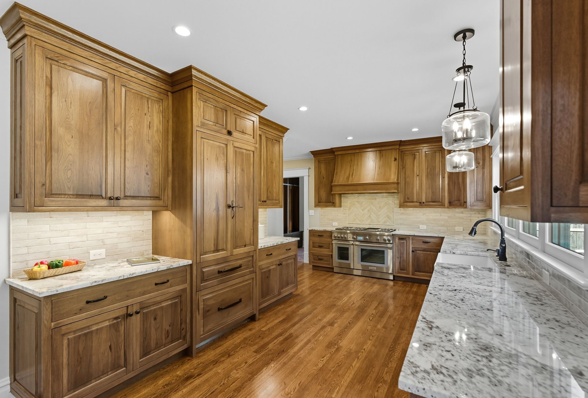 Spacious kitchen with wood cabinets, granite countertops, stainless steel appliances, and a light-colored tile backsplash.