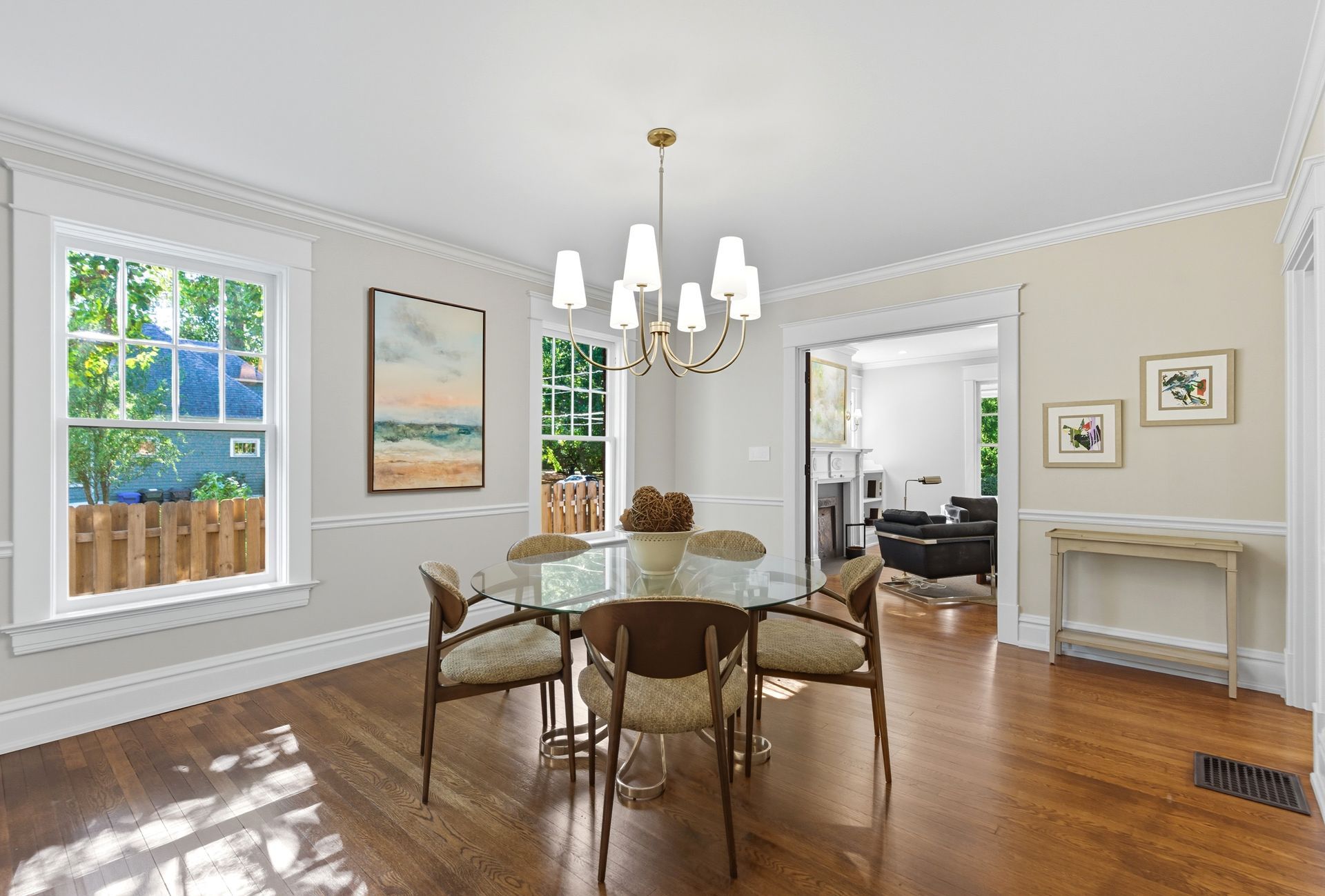 Formal dining room with a round glass table, chairs, and a chandelier.