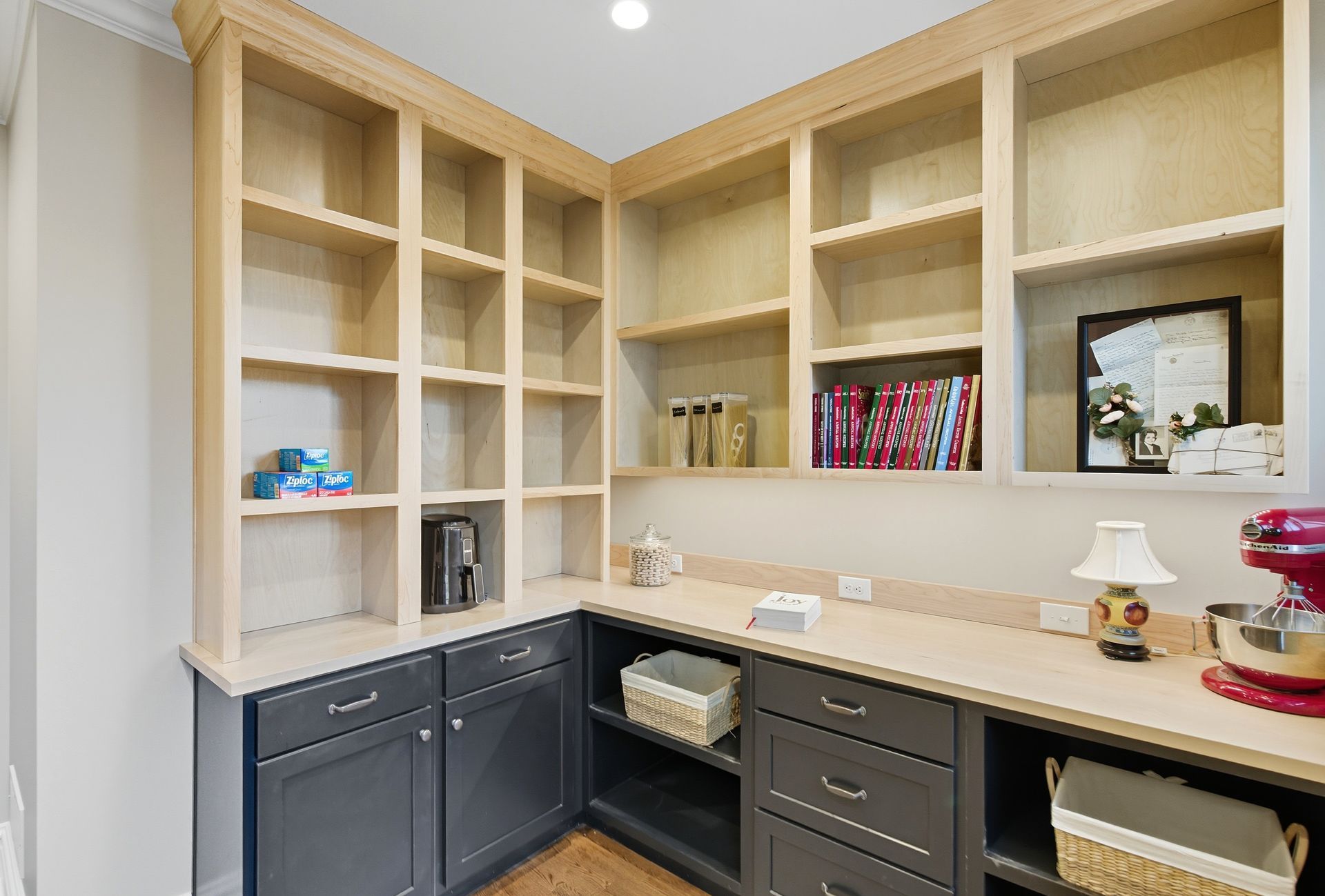 Corner pantry with gray cabinets, light wood shelves, and a neutral countertop.