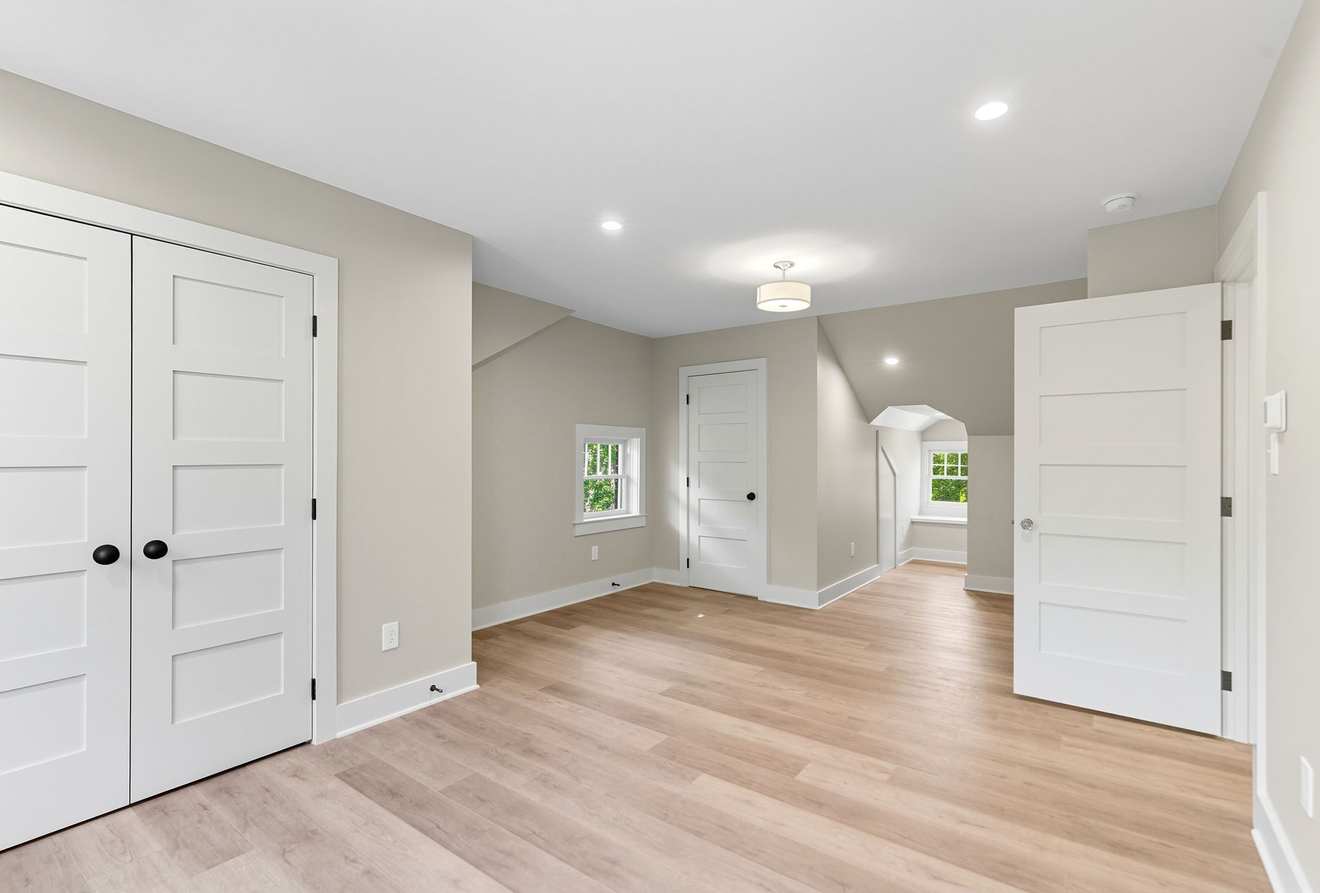 Bright room with light wooden floors, white doors, and neutral walls.