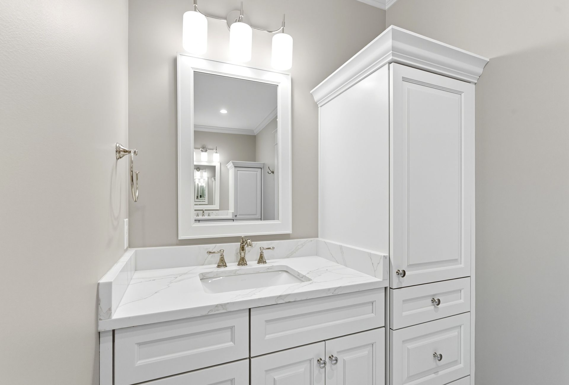 White bathroom vanity with sink, mirror, and storage cabinet.