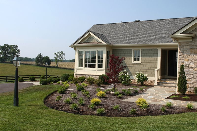 House exterior with landscaping: beige siding, stone accents, and a garden.
