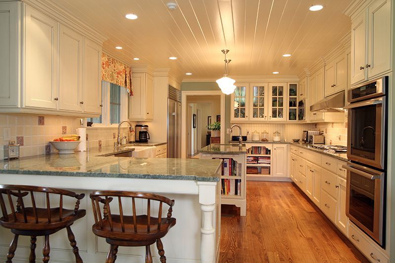 White kitchen with wooden floors, granite countertops, and bar stools.