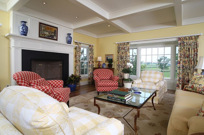 Living room with fireplace, armchairs, and sofa in a yellow and floral color scheme.