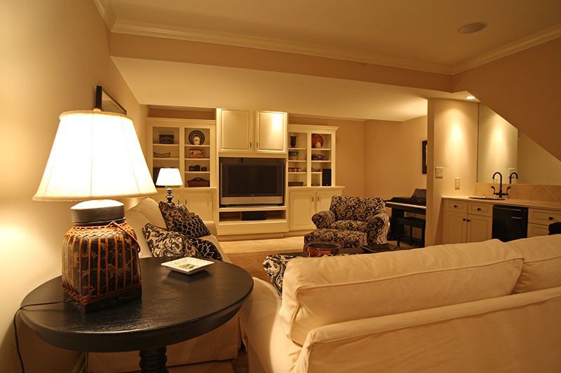 Cozy living room with neutral colors, sofa, lamp, TV, cabinets, and a wet bar.