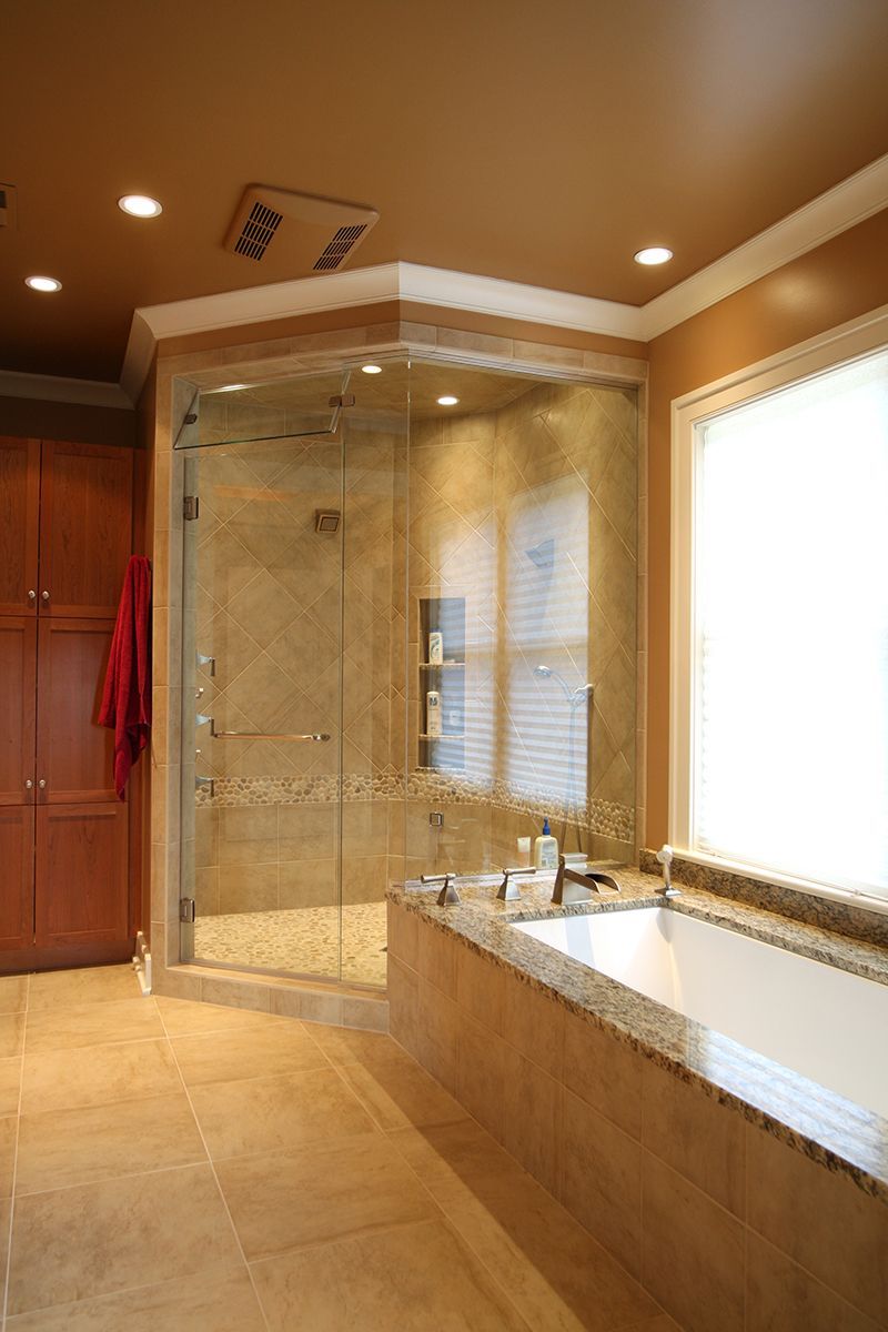 Luxurious bathroom with a glass shower, bathtub, and wooden cabinets.