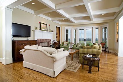 Living room with light wood floors, fireplace, beige walls, and a large screen TV.