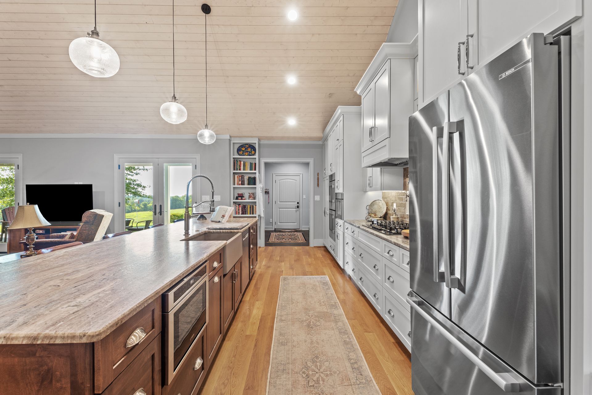 A modern kitchen with a large island, white cabinets, and stainless steel appliances.