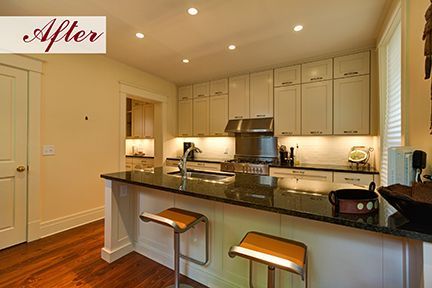 Modern kitchen with white cabinets, dark countertop, and a breakfast bar with stools.