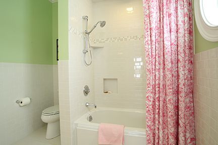 Bathroom with pink floral shower curtain, white fixtures, and pale green and white walls.