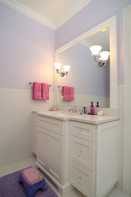 Bathroom with white vanity, lavender walls, pink towels, and a purple rug.