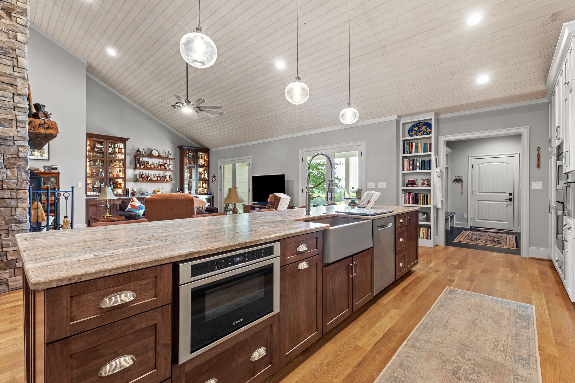 Spacious kitchen with large island, built-in oven, wood cabinets, and pendant lights.