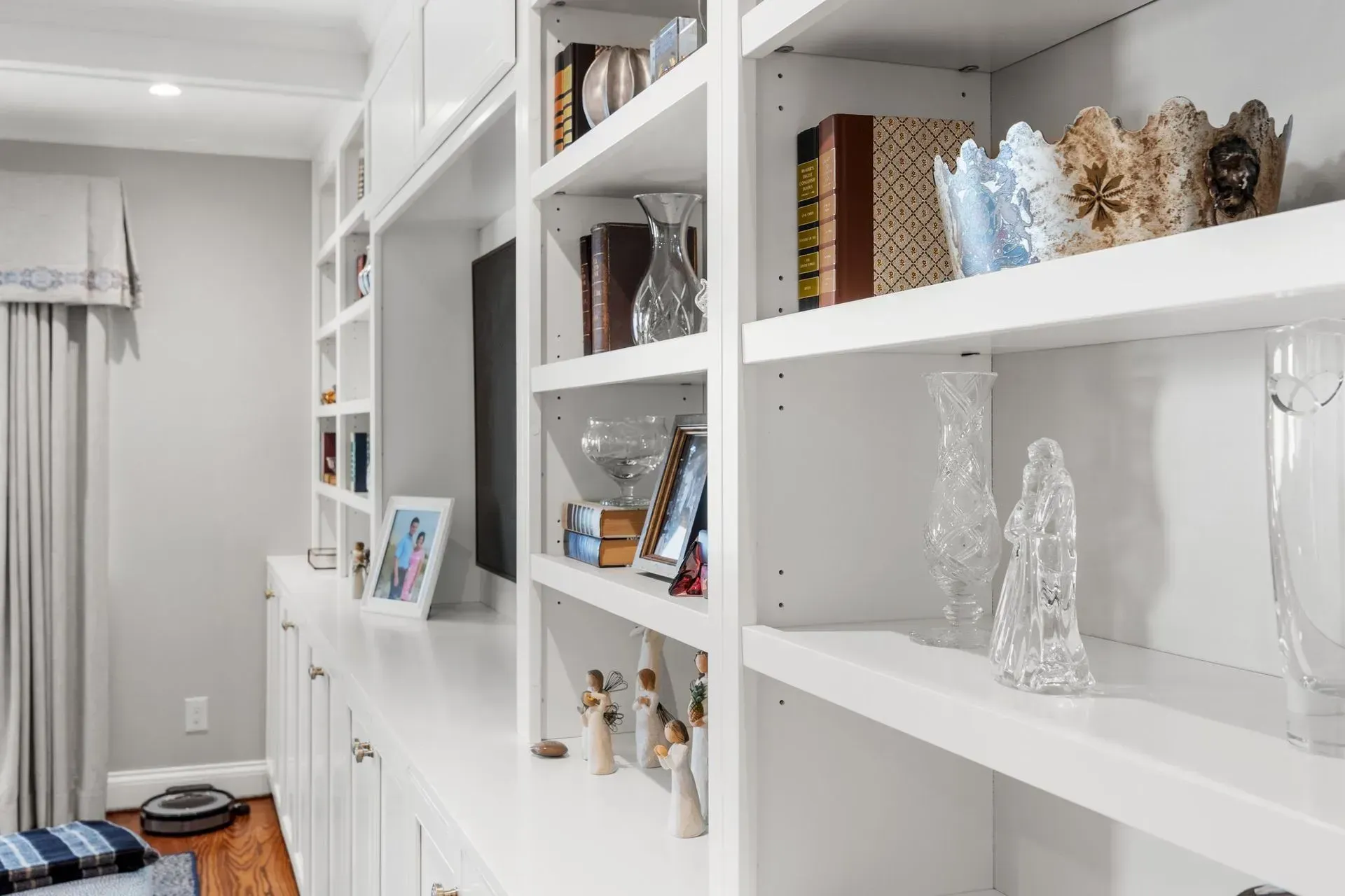 White built-in shelves holding books, decorations, and a framed photo. A TV is in the center.