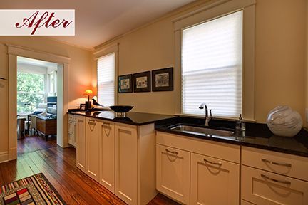 Renovated kitchen with white cabinets, black countertop, sink, and three framed pictures.