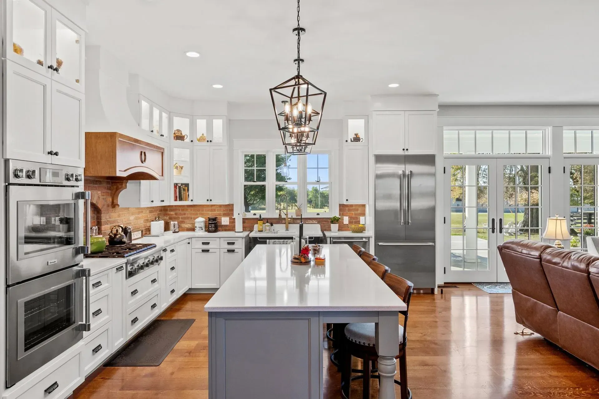 Bright white kitchen with island, stainless steel appliances, and French doors leading to a yard.