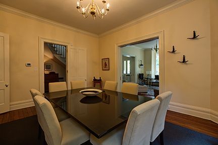 Dining room with a dark table, cream chairs, and a chandelier. Includes a view into another room.