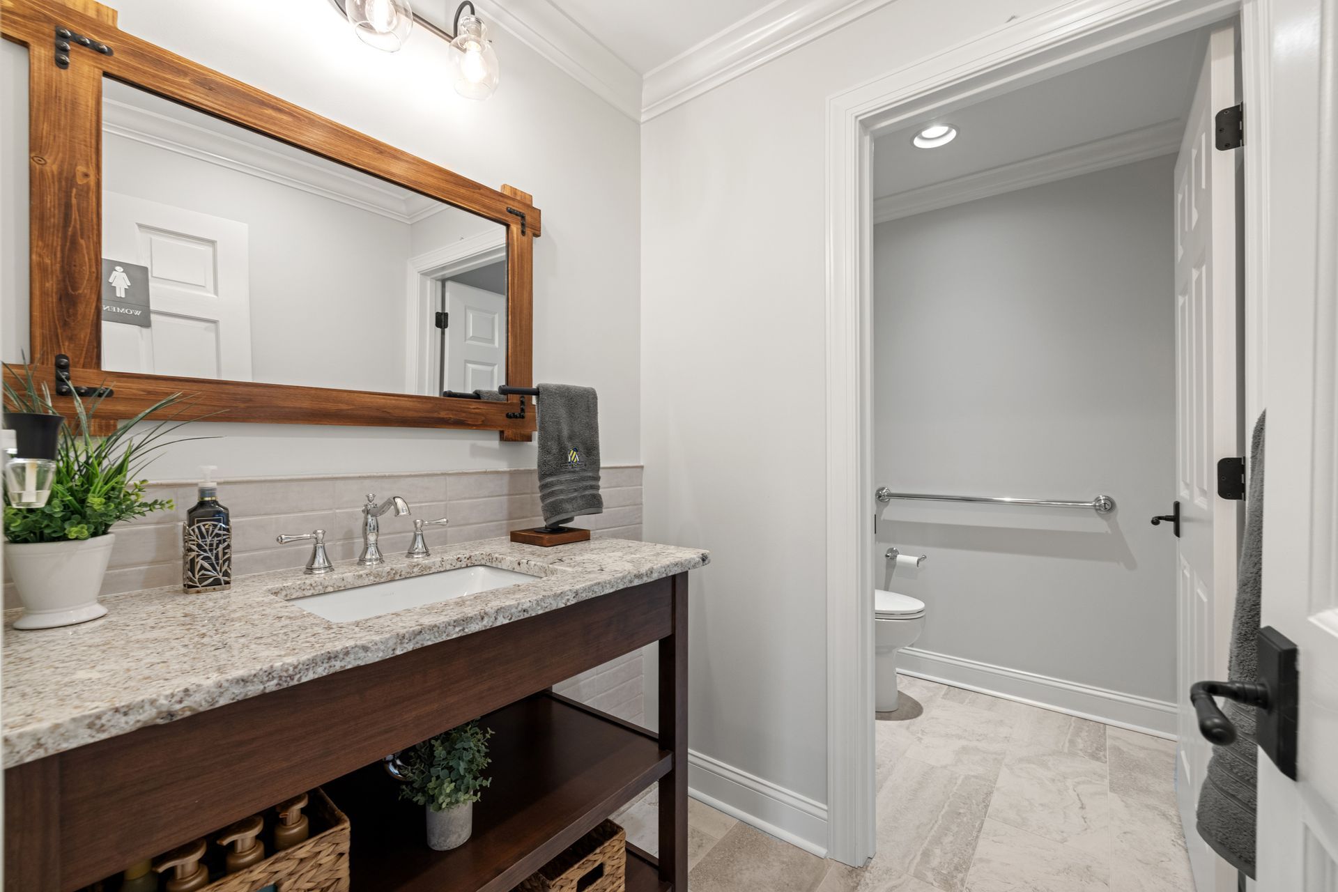 Bathroom with a wooden vanity, mirror, and adjacent toilet room.