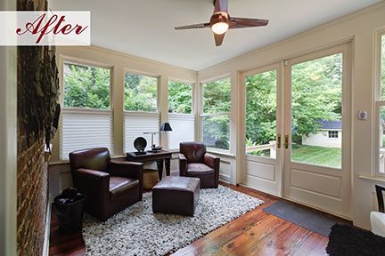 Sunroom with two brown leather armchairs, an ottoman, and a rug, with windows overlooking a yard.