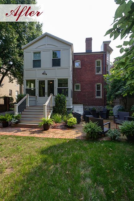 Backyard with a two-story addition to a brick house, featuring a patio, steps, and landscaping.