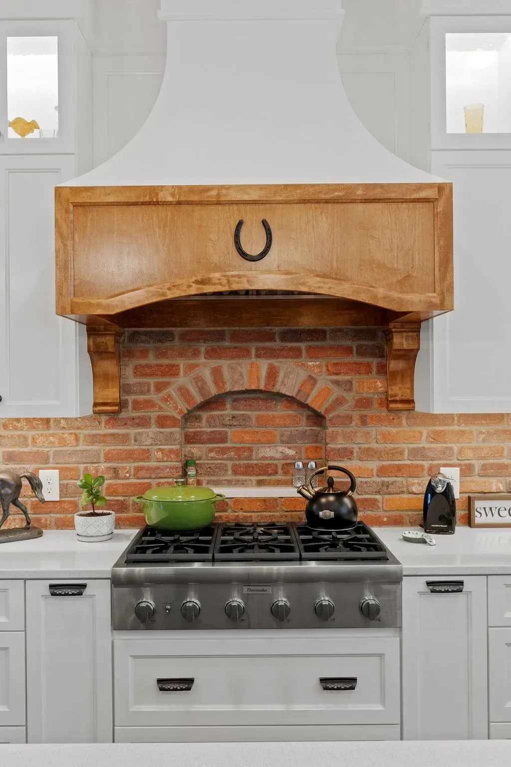 Kitchen with a brick backsplash, wooden range hood, and a gas stove.
