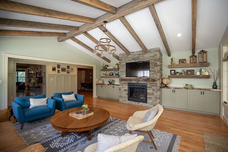Living room with blue armchairs, fireplace, wood beams, and light green walls.