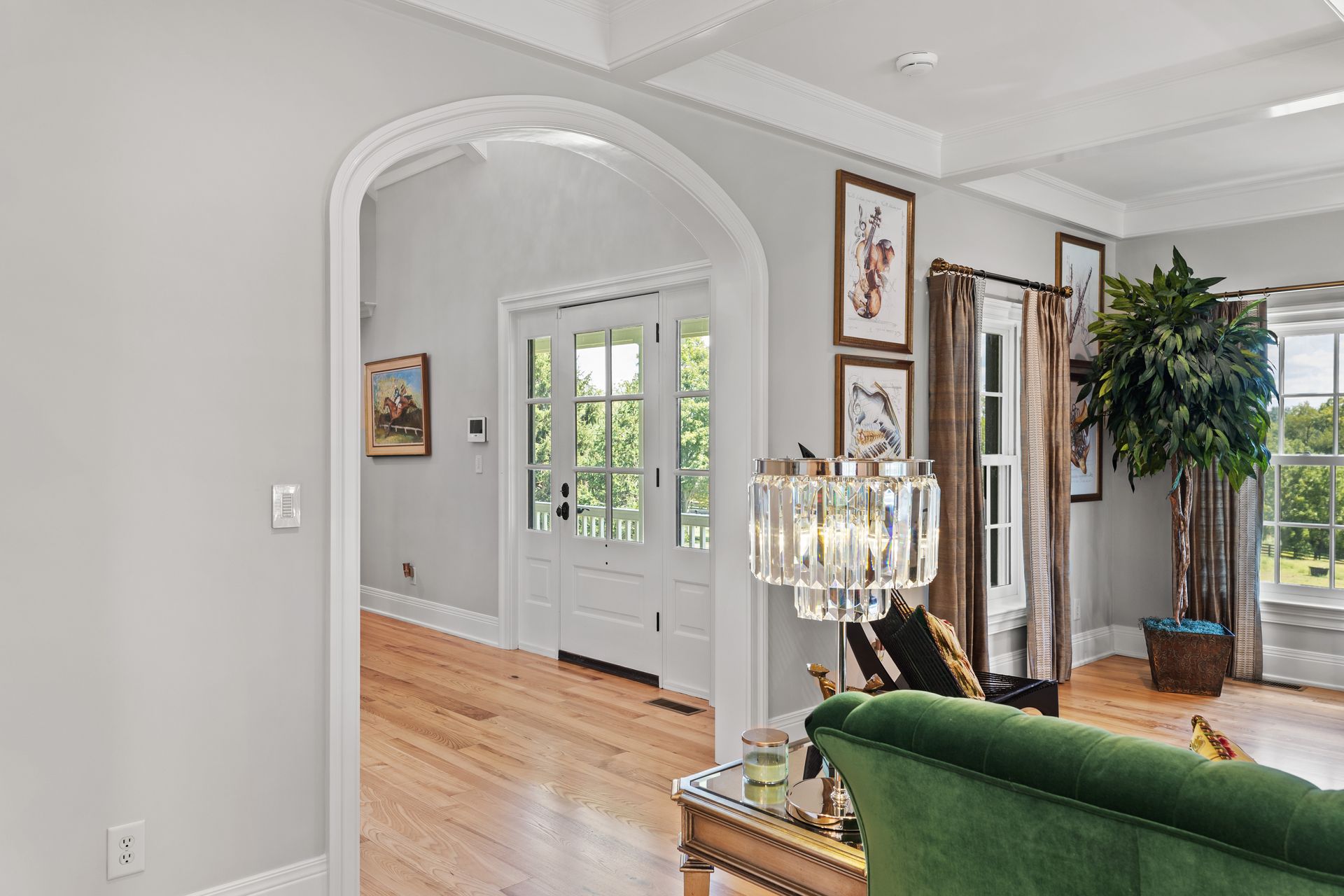 Living room with arched doorway, wooden floors, and green sofa.