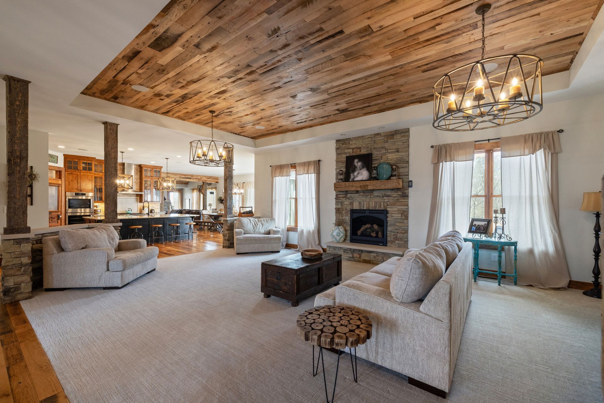 Cozy living room with stone fireplace, wooden ceiling, and neutral-toned furniture.
