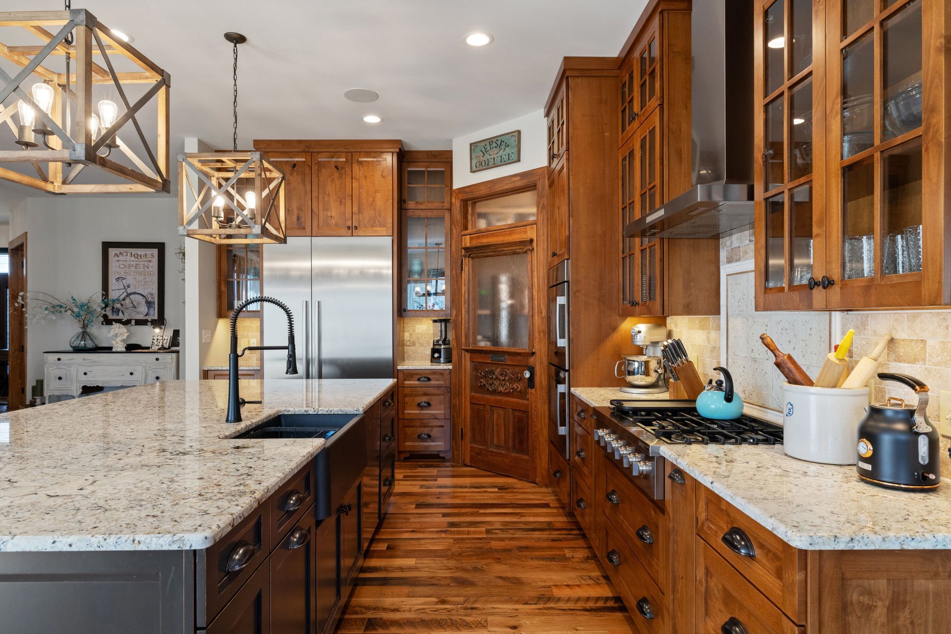 Wooden kitchen with island, cabinets, stainless steel appliances, and patterned backsplash.