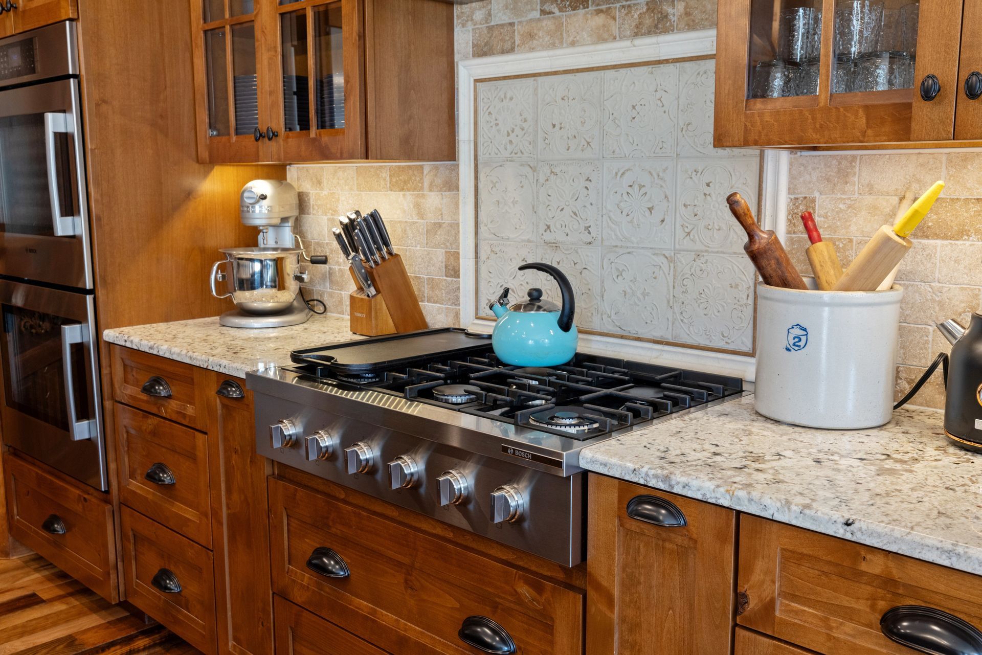 Kitchen with wooden cabinets, granite countertops, and a stainless steel gas range. A blue kettle sits on the range.