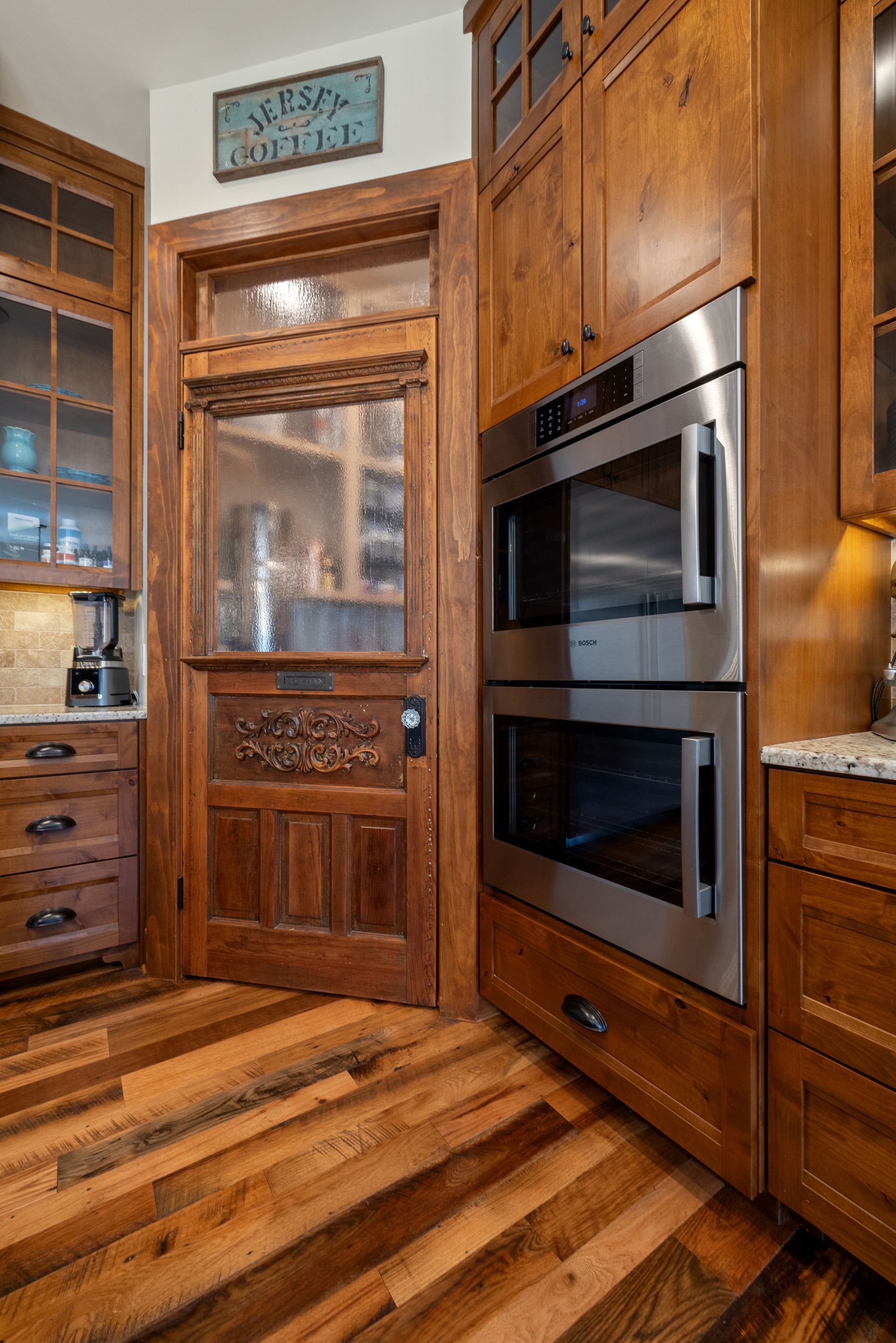 Rustic kitchen with wood cabinets, double oven, and antique door.