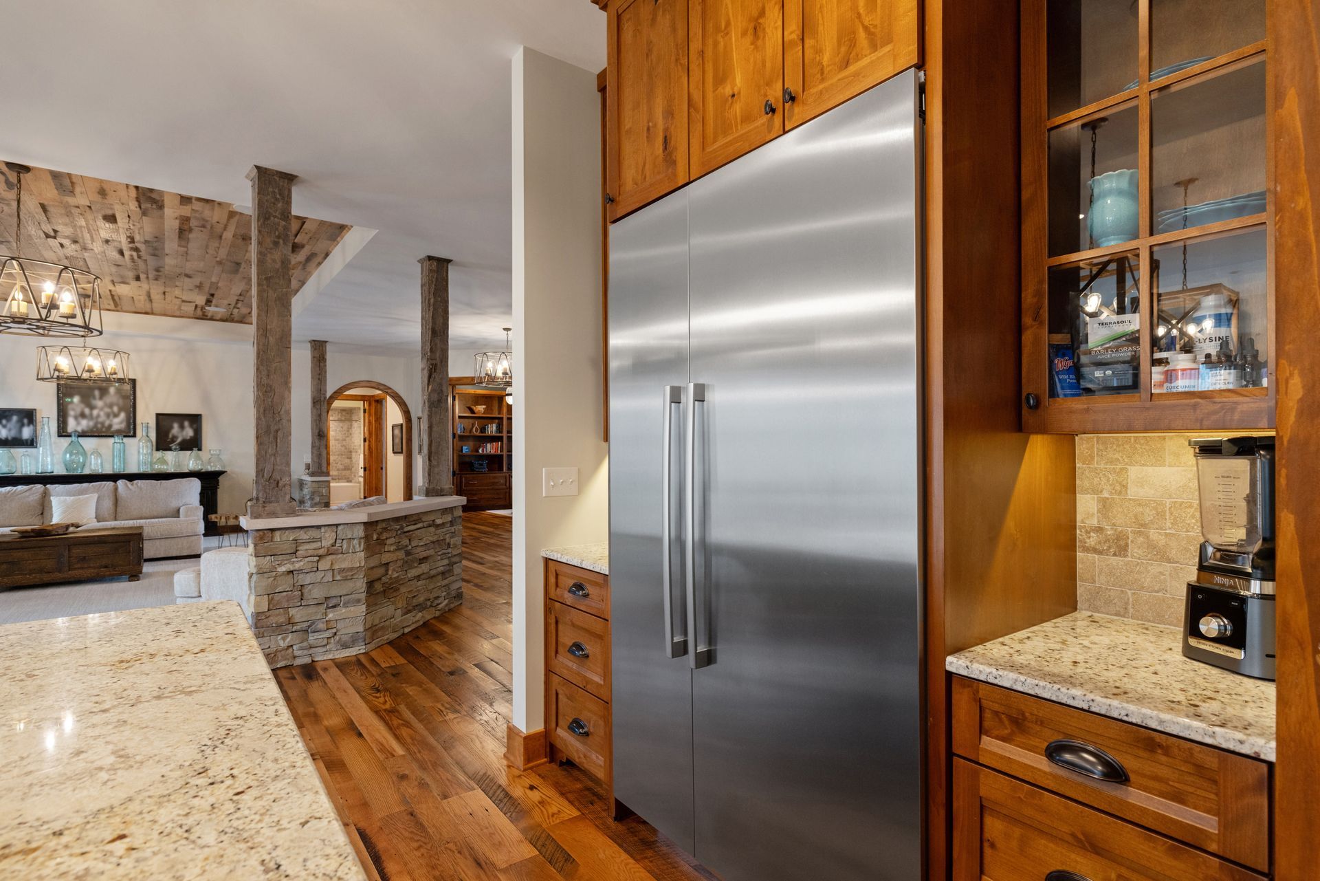 Kitchen interior with a stainless steel refrigerator, wood cabinetry, and stone accents.