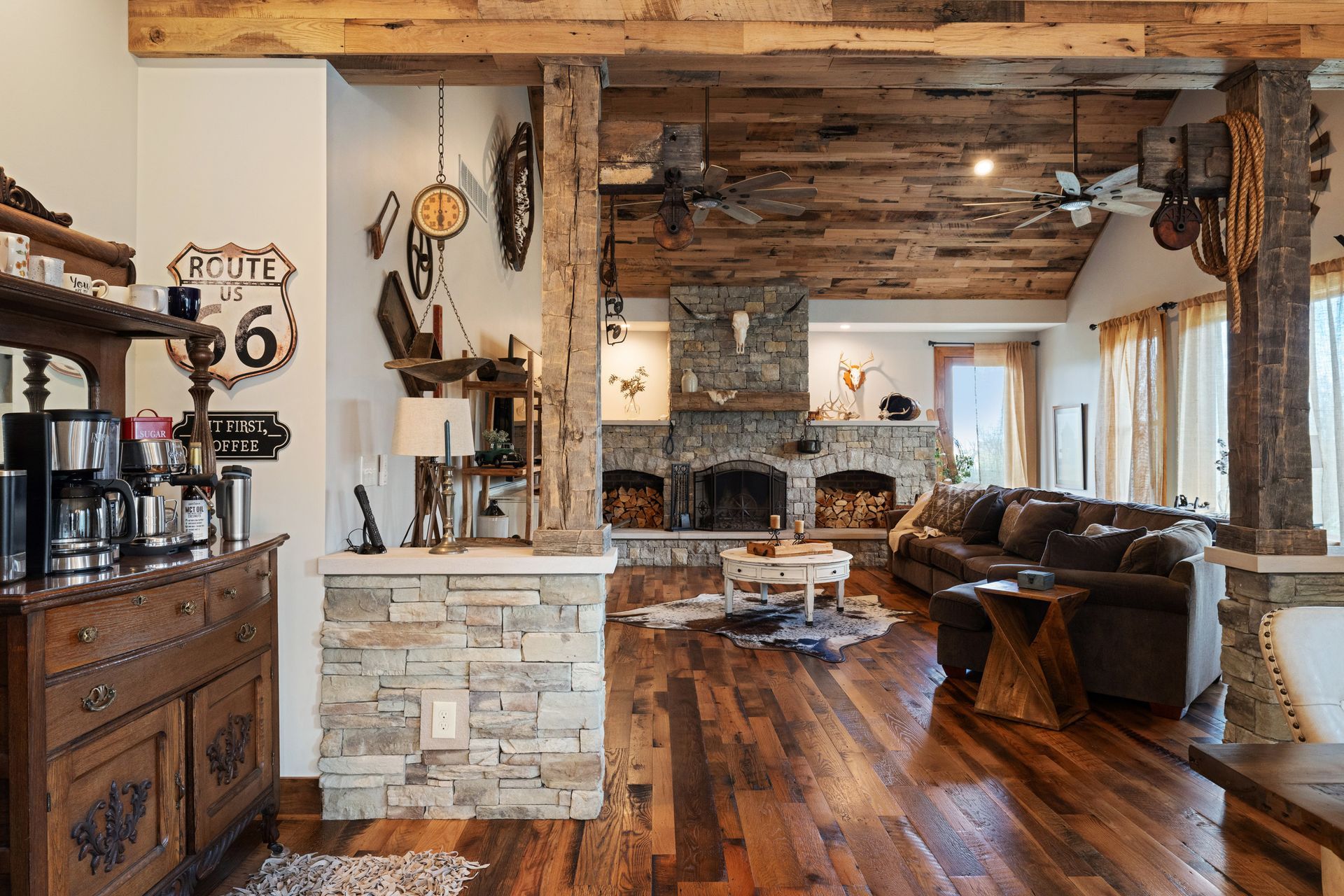 Rustic living room with wood floors, stone fireplace, exposed beams, and decorative Route 66 sign.