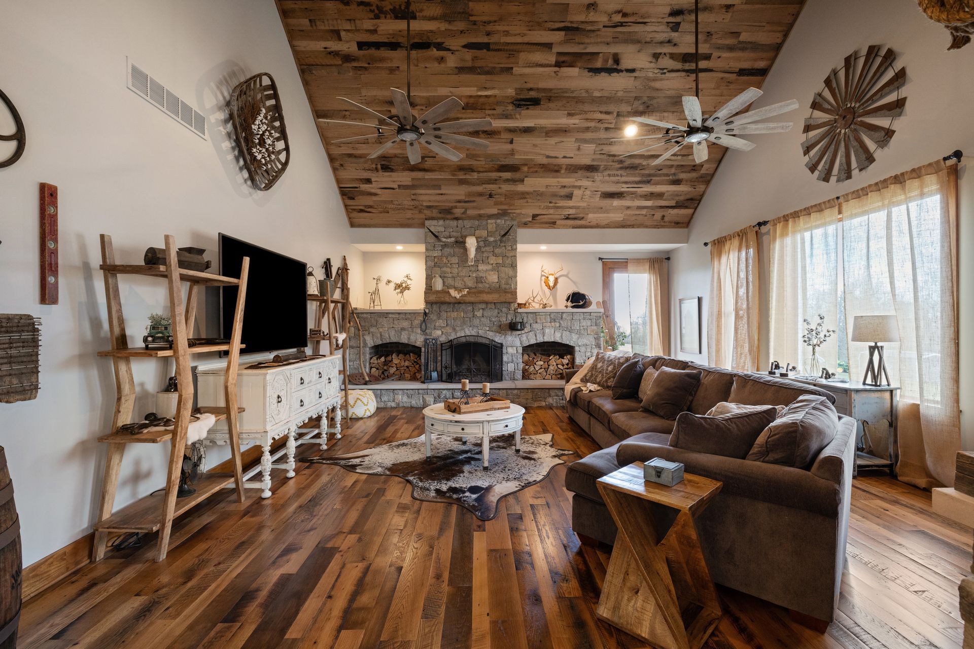 Living room with wood ceiling, fireplace, brown sofa, and hardwood floors.