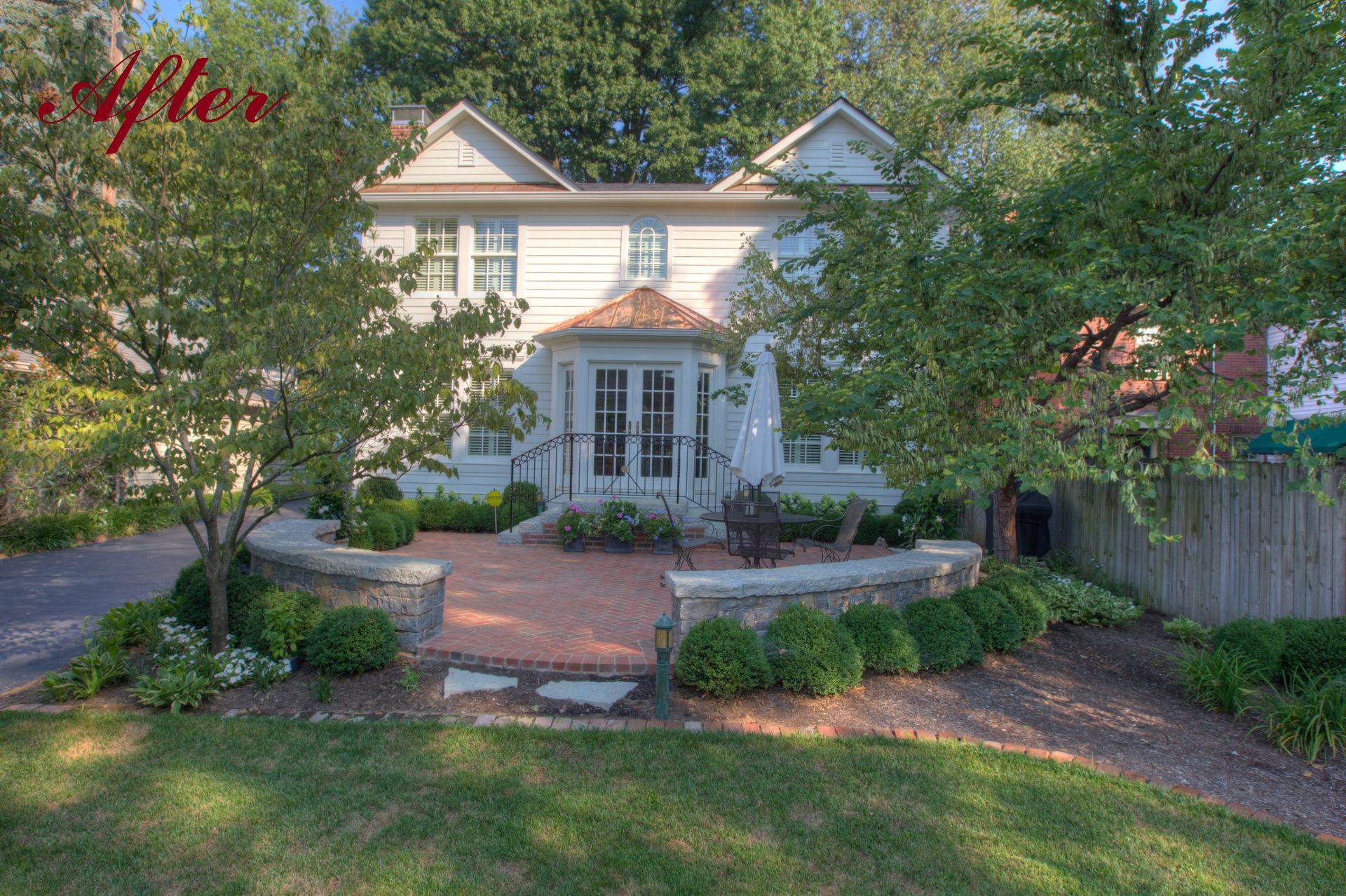 A white two-story house with brick pathway and landscaping. 