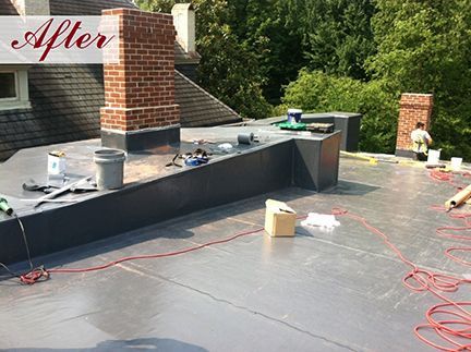 A flat roof after repairs, with brick chimneys, tools, and a worker.