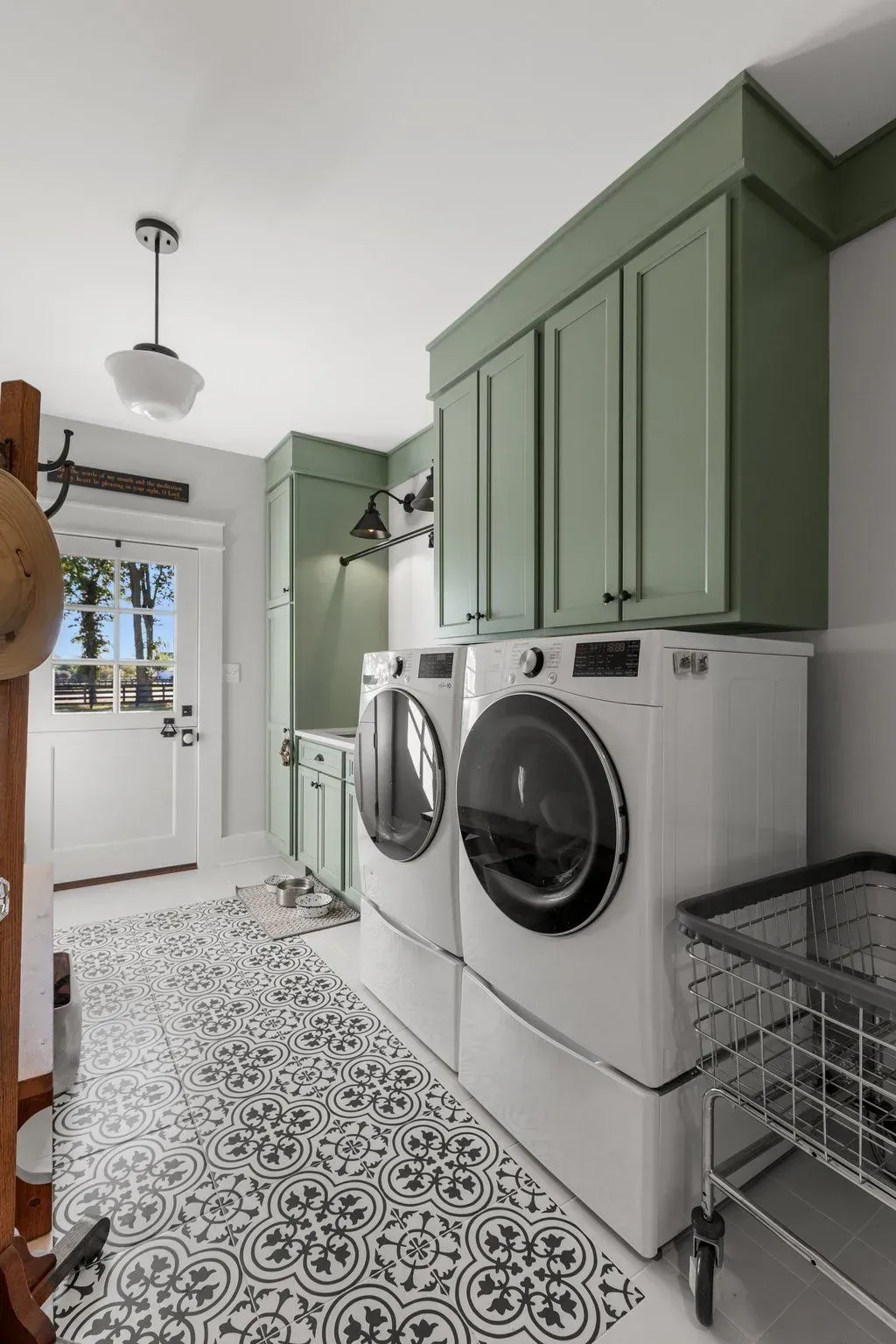 Laundry room with green cabinets, white appliances, patterned floor, and white door.