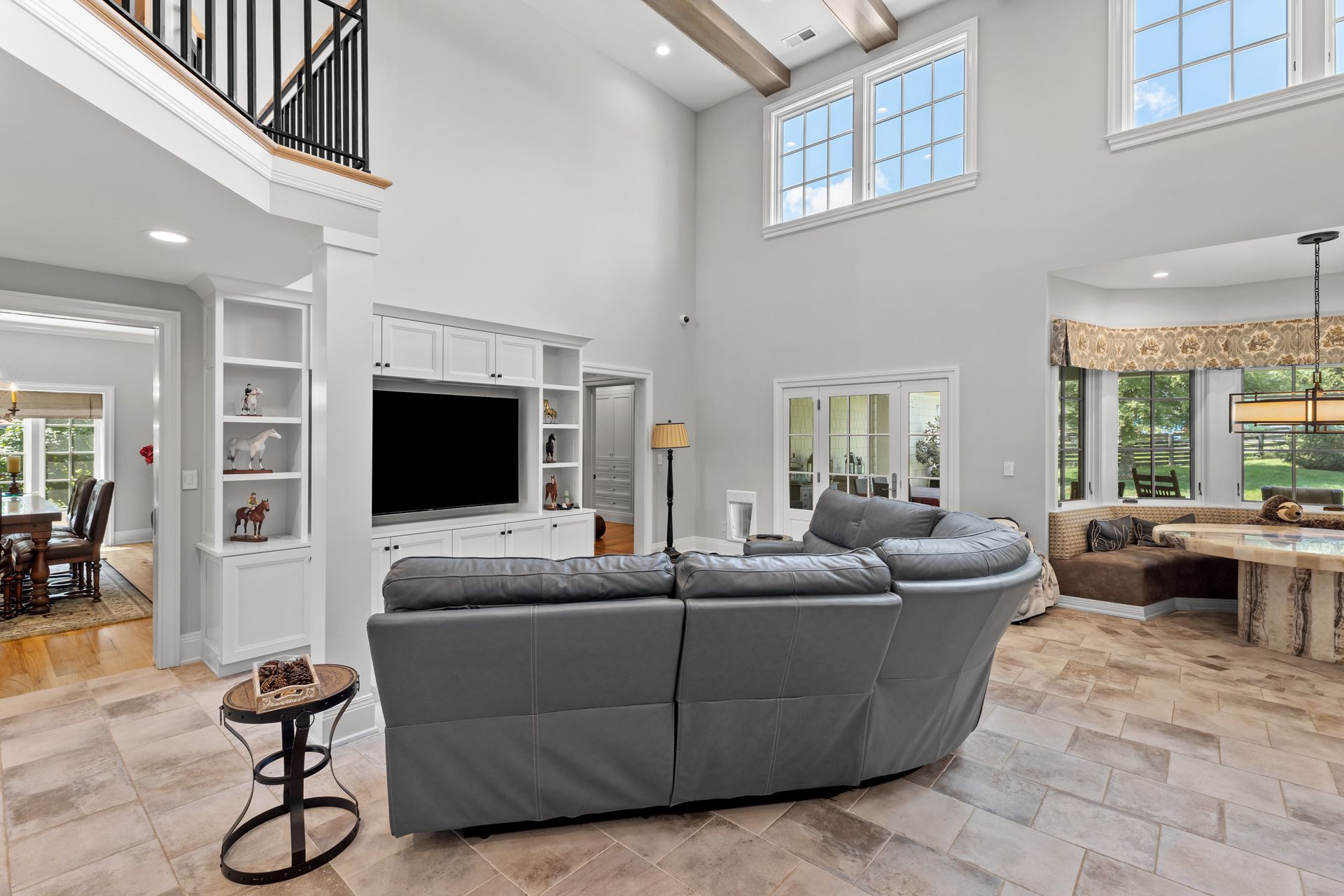 Spacious living room with gray sofa, TV, and high windows; neutral tones and natural light.
