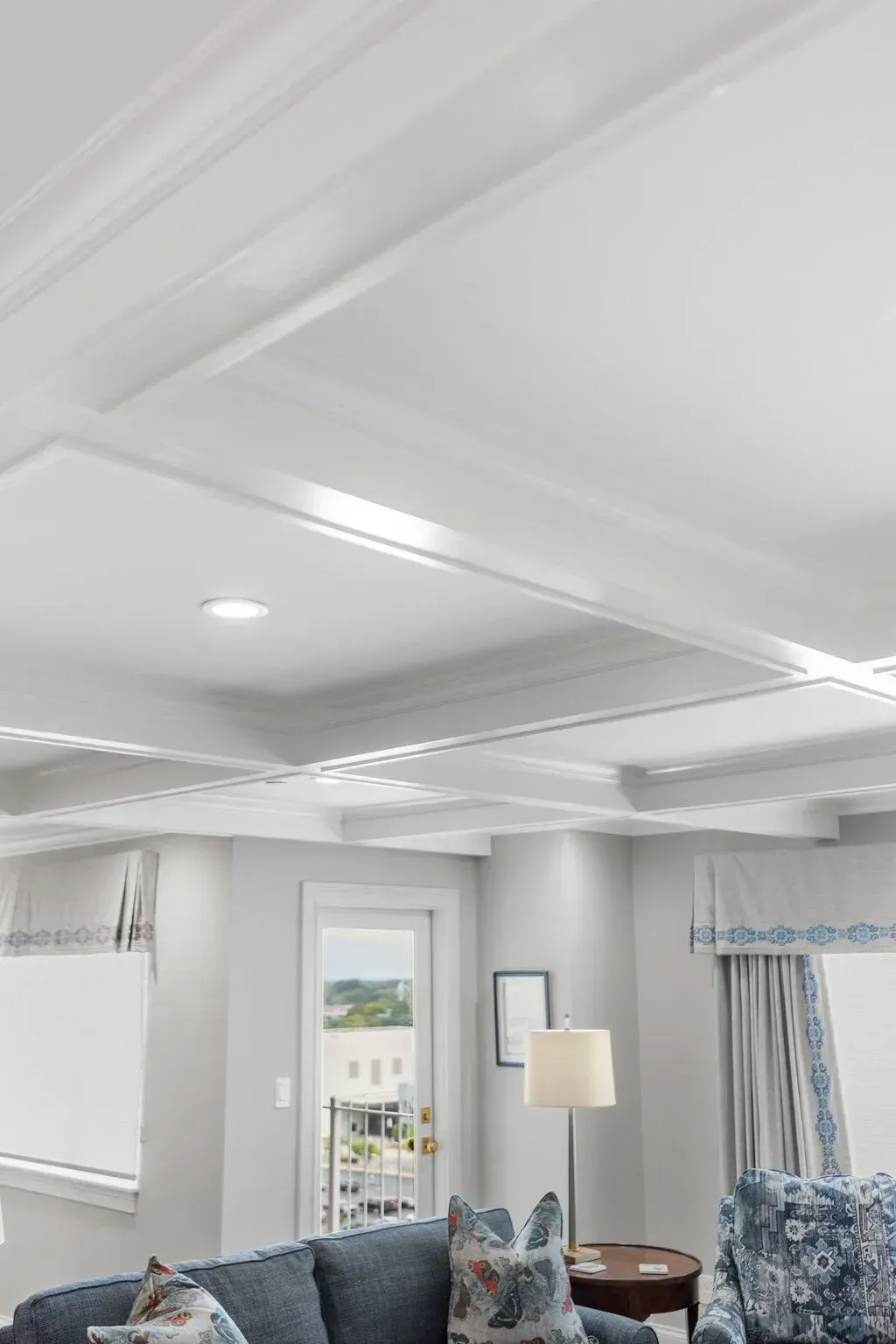 Living room with coffered ceiling, blue furniture, and a doorway to an outdoor view.