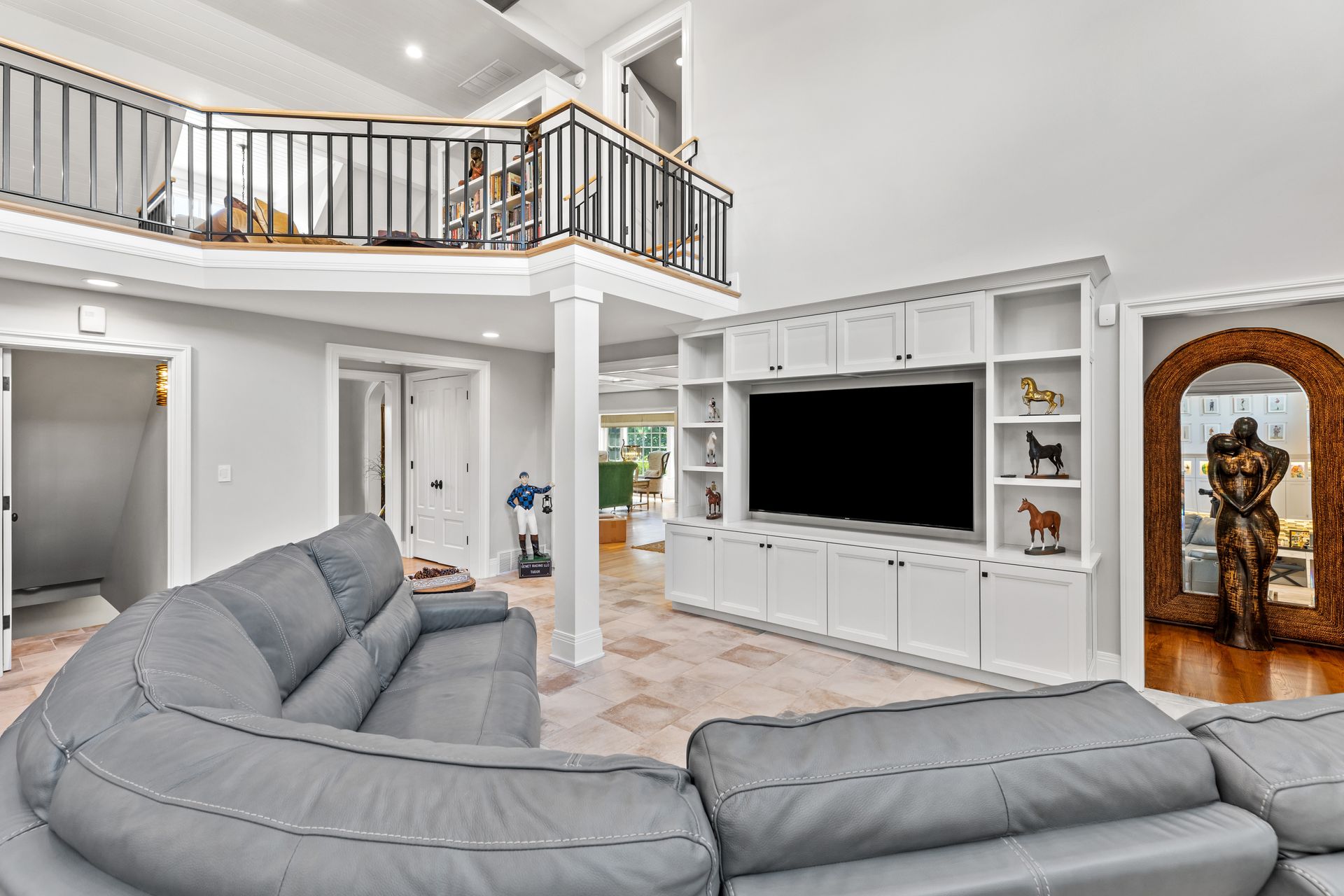 Living room with gray sectional sofa, built-in white entertainment center, and a loft area.