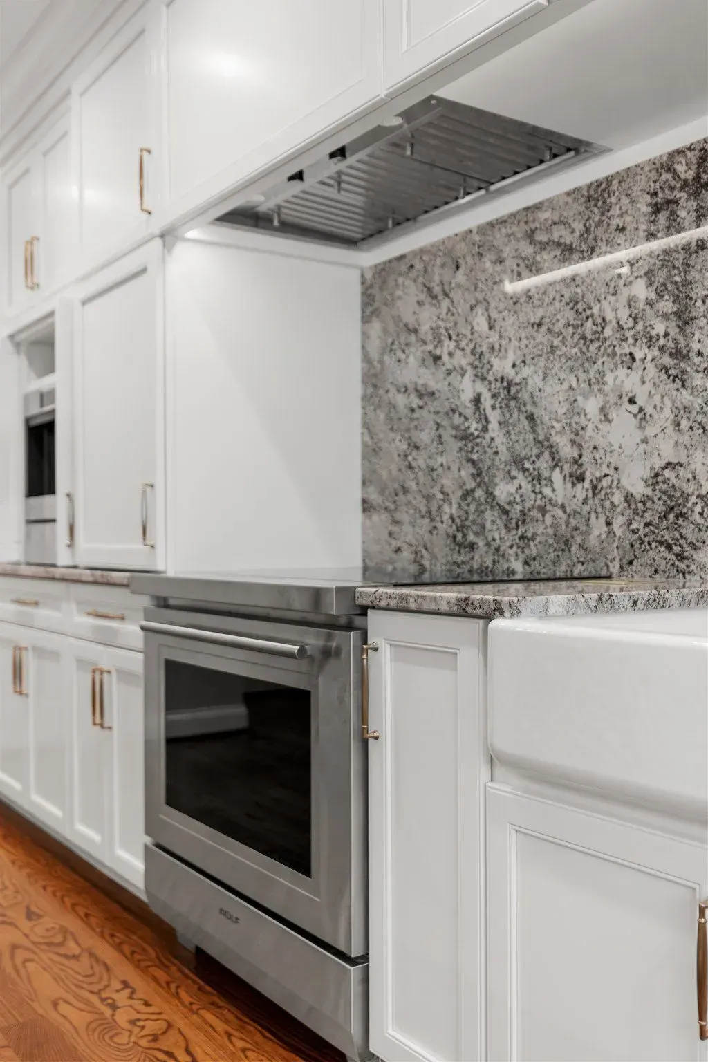White kitchen with stainless steel oven, cabinets, and backsplash.