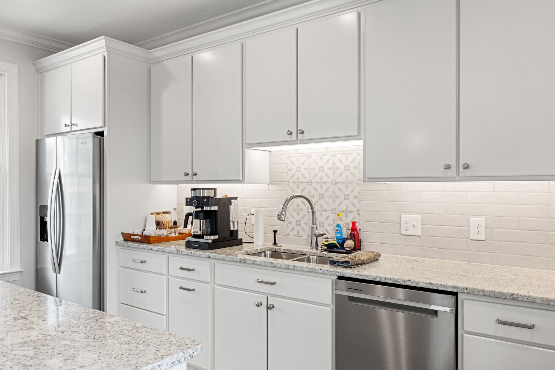 White kitchen with stainless steel appliances, white cabinets, and granite countertops.