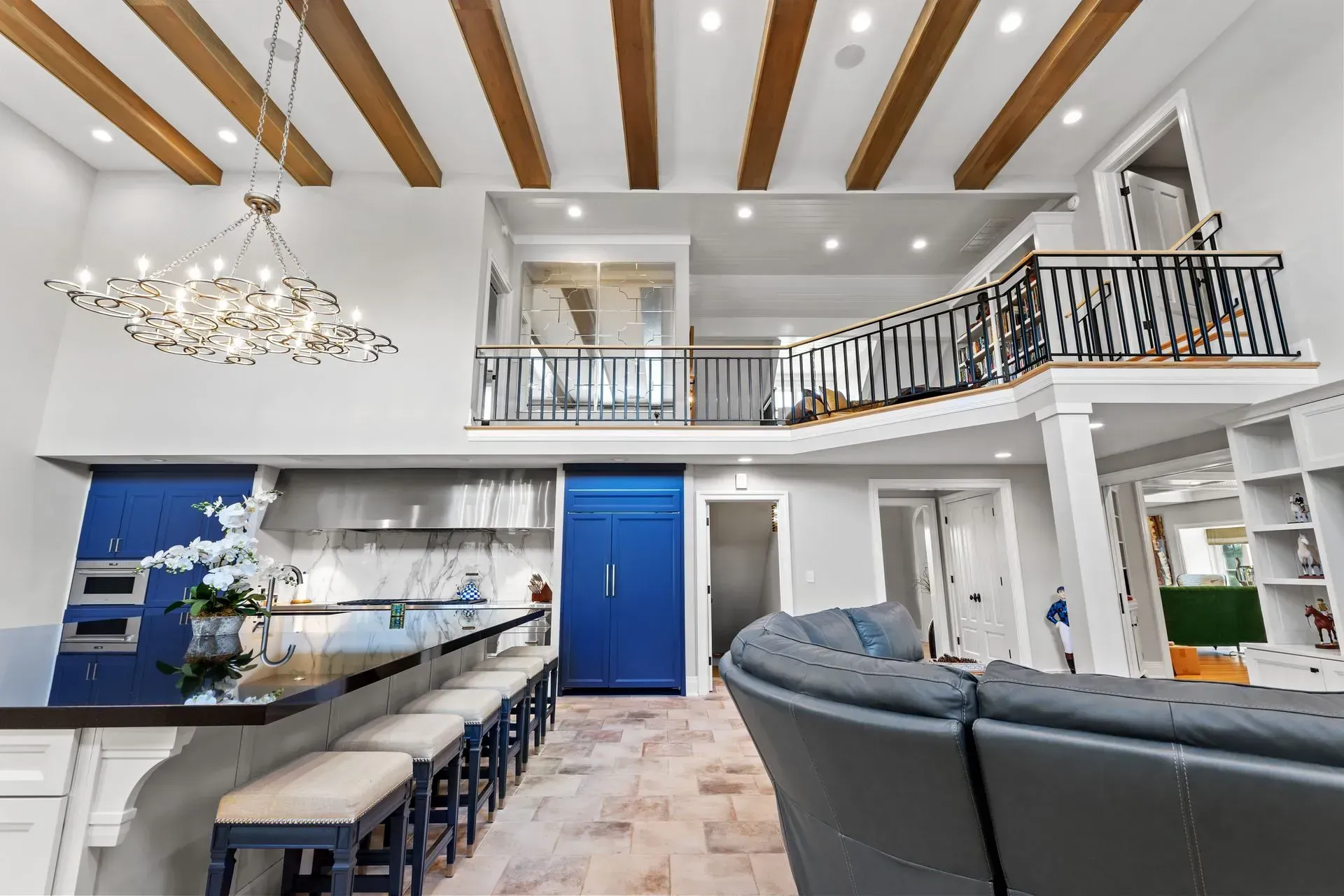 Open-concept kitchen with a loft. Features a blue refrigerator, island with bar stools, and a chandelier.