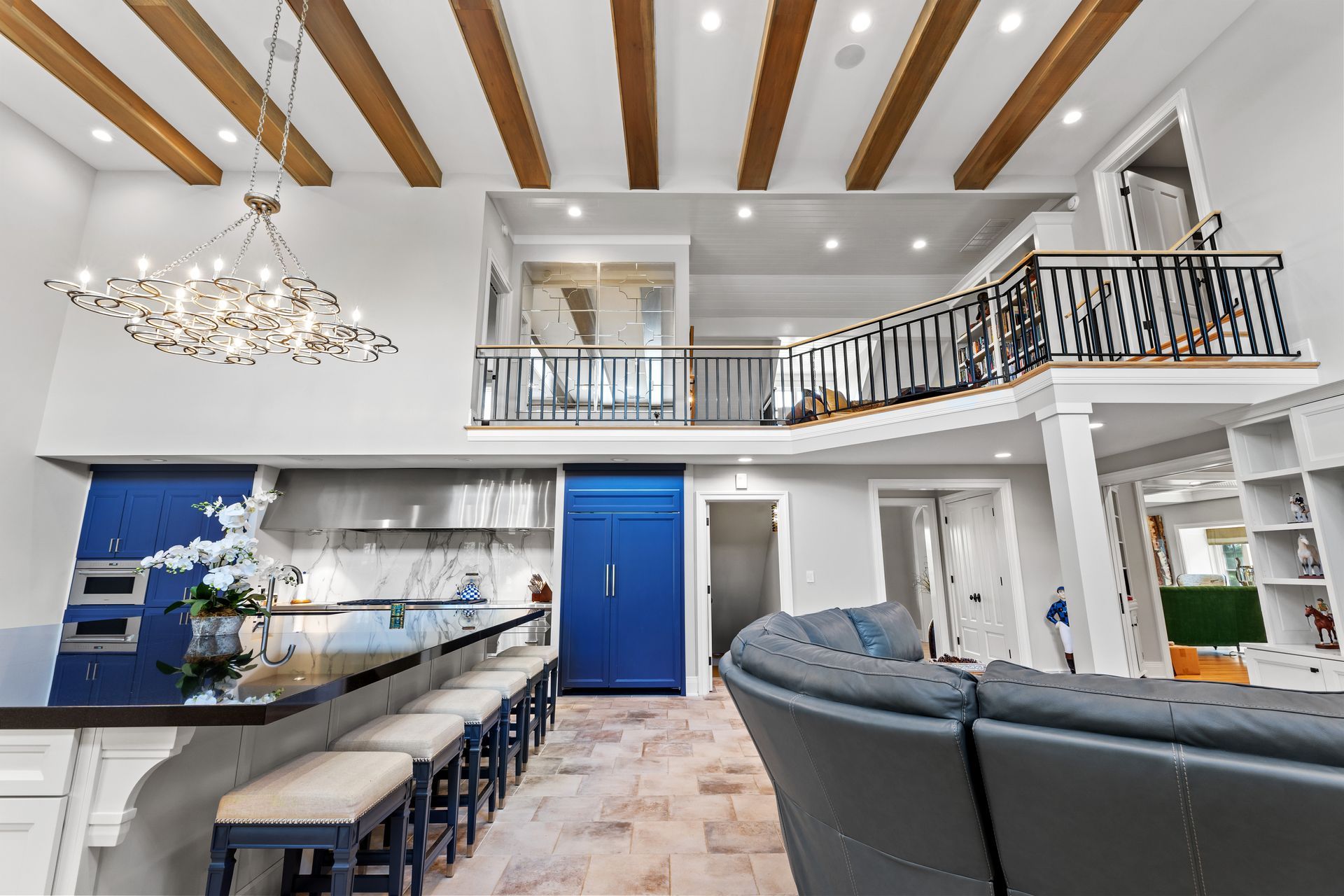 Spacious kitchen and living area with a balcony. Blue accent wall, beams, and a chandelier.