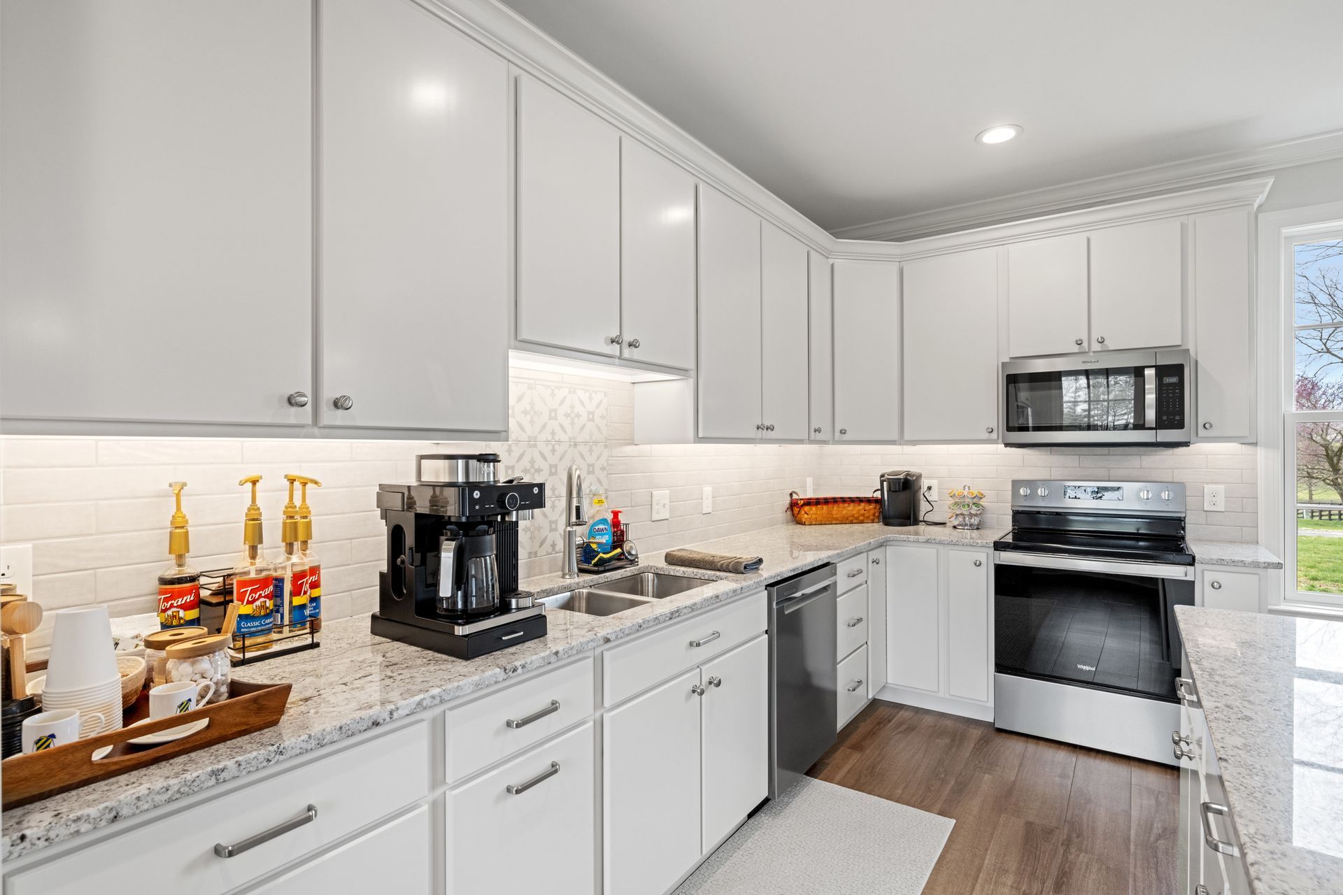 White kitchen with cabinets, appliances, and a coffee station.