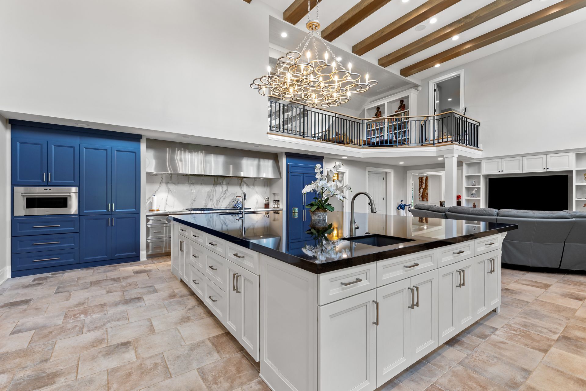 Luxurious modern kitchen with blue cabinetry, large island, high ceilings, and a balcony.