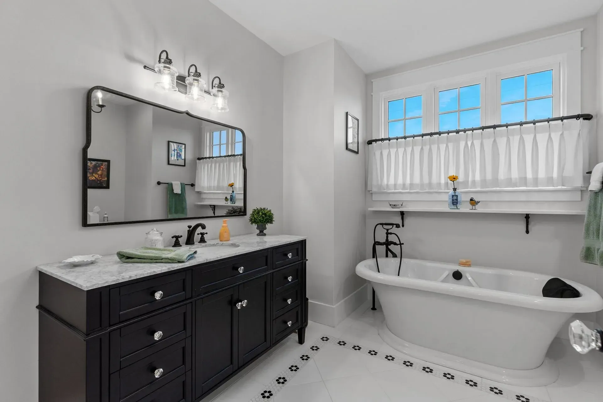 Bathroom with black vanity, white tub, and decorative window.