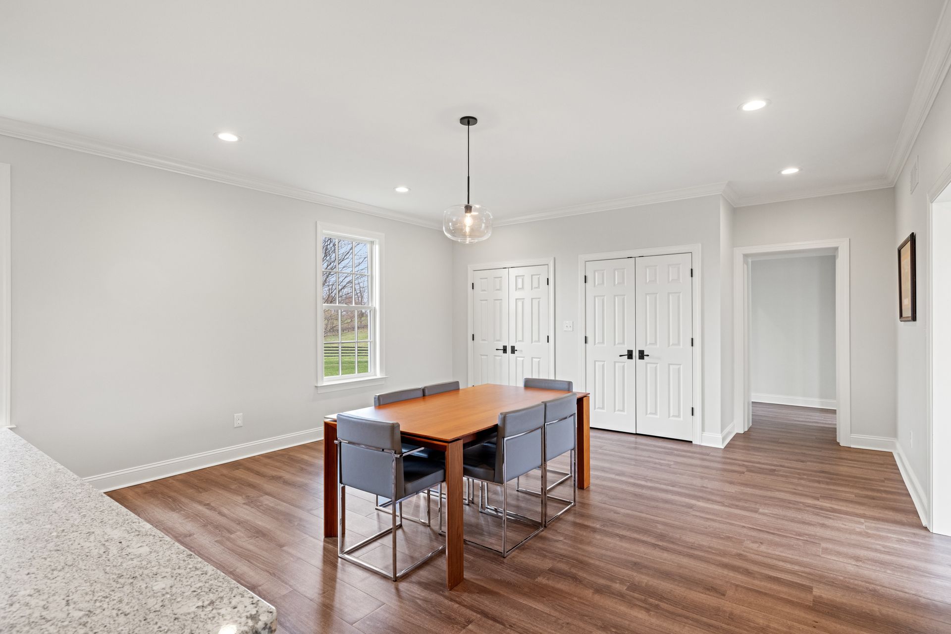 Dining room with wooden table, gray chairs, hardwood floors, and white walls.