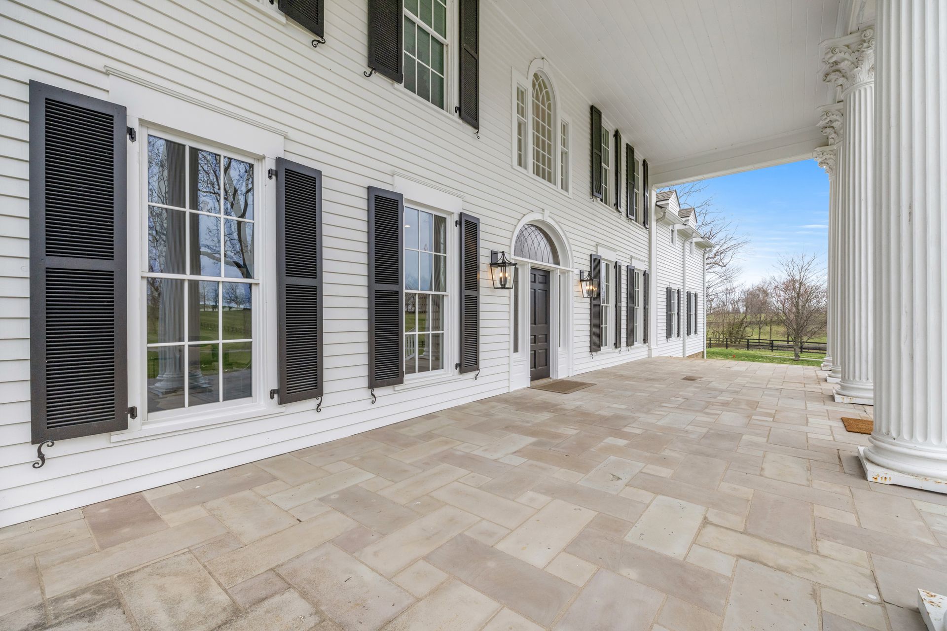 White two-story house with black shutters, large columns, and a stone porch.