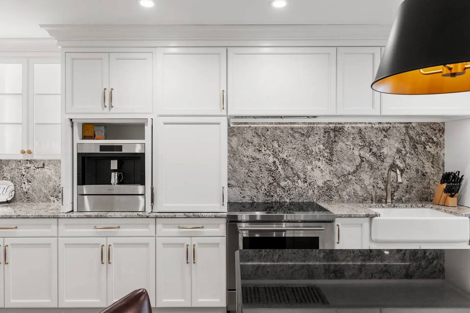 White kitchen with granite countertops, stainless steel appliances, and gold accents.