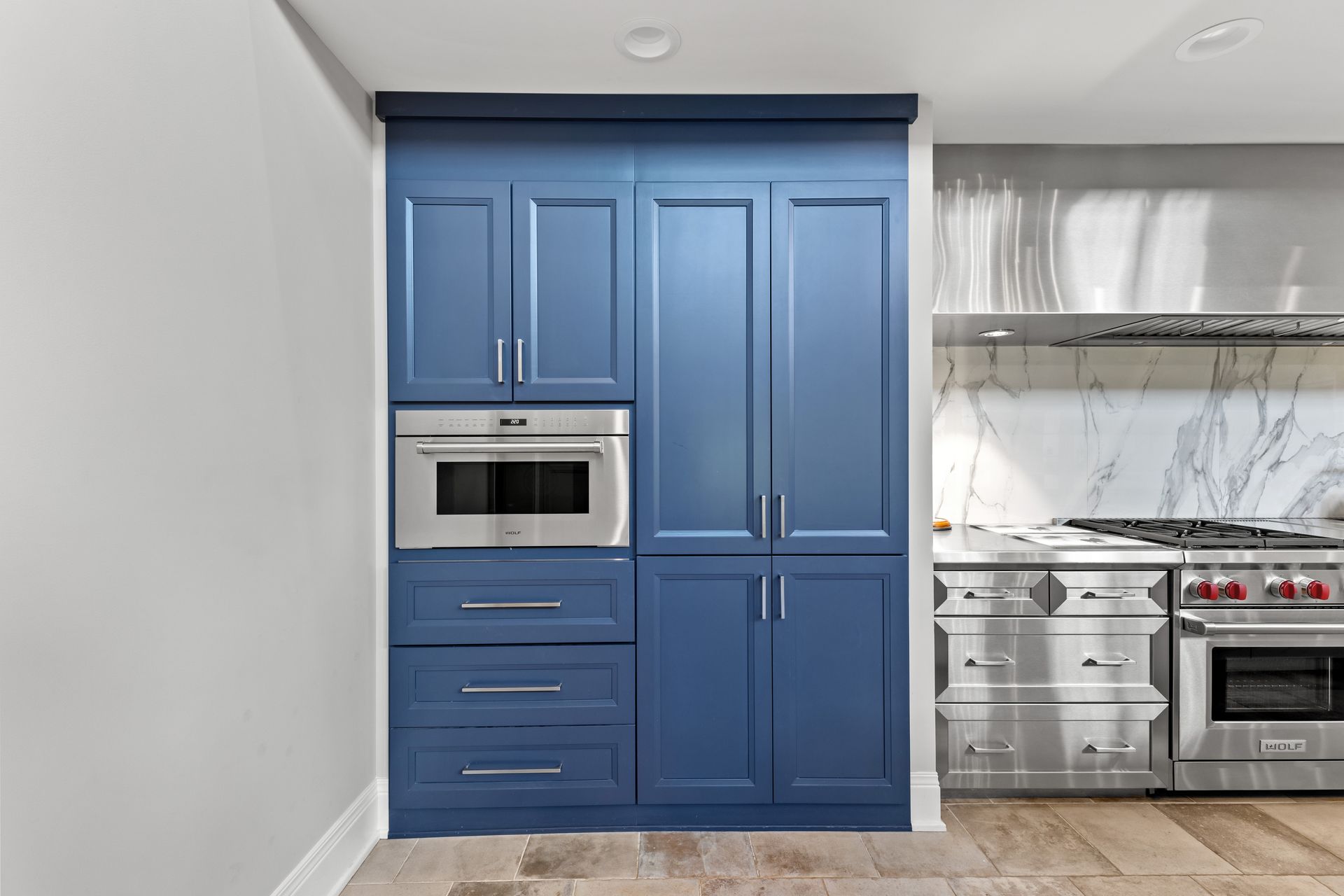 Blue kitchen pantry cabinet with a microwave and drawers.